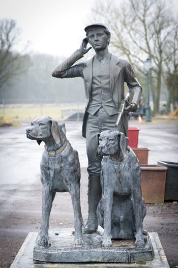 lot 567 -A contemporary life-size bronze sculpture of a huntsman with two hounds